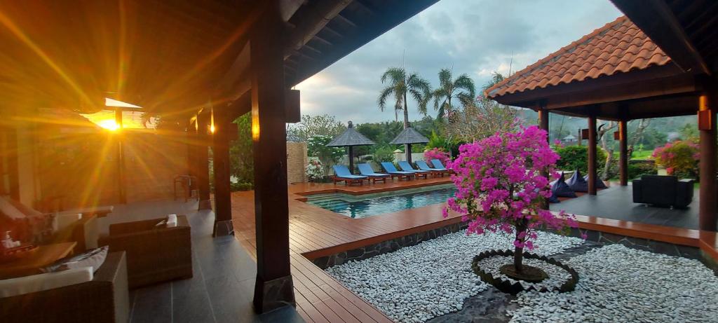 una casa con piscina y un árbol con flores rosas en Bale Solah Lombok Holiday Resort, en Senggigi 