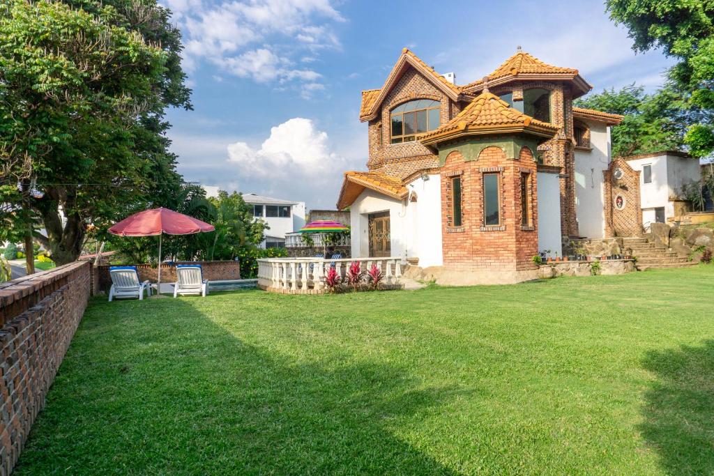 a large house with a grass yard with an umbrella at Castillo San Carlos Lomas de Cocoyoc con Cancha de Padel 16Huespedes in Cocoyoc