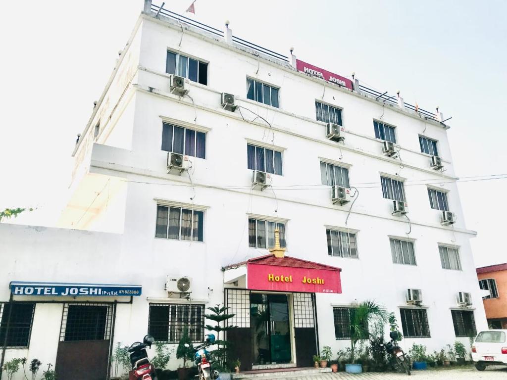a white building with a red sign in front of it at Hotel Joshi in Bhairāhawā