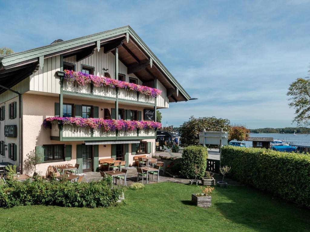 une maison avec des fleurs sur ses balcons dans l'établissement Hotel Garni Möwe am See, à Prien am Chiemsee