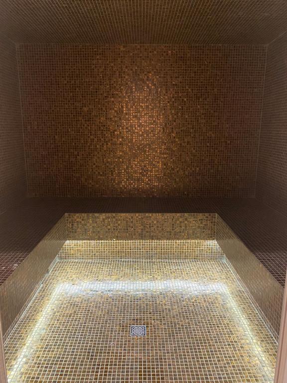 a bathroom with a shower with a tiled wall at Greif Hotel Maria Theresia in Trieste