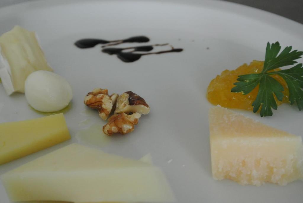 a white plate with cheese and other foods on it at Hotel Bologna in Lignano Sabbiadoro