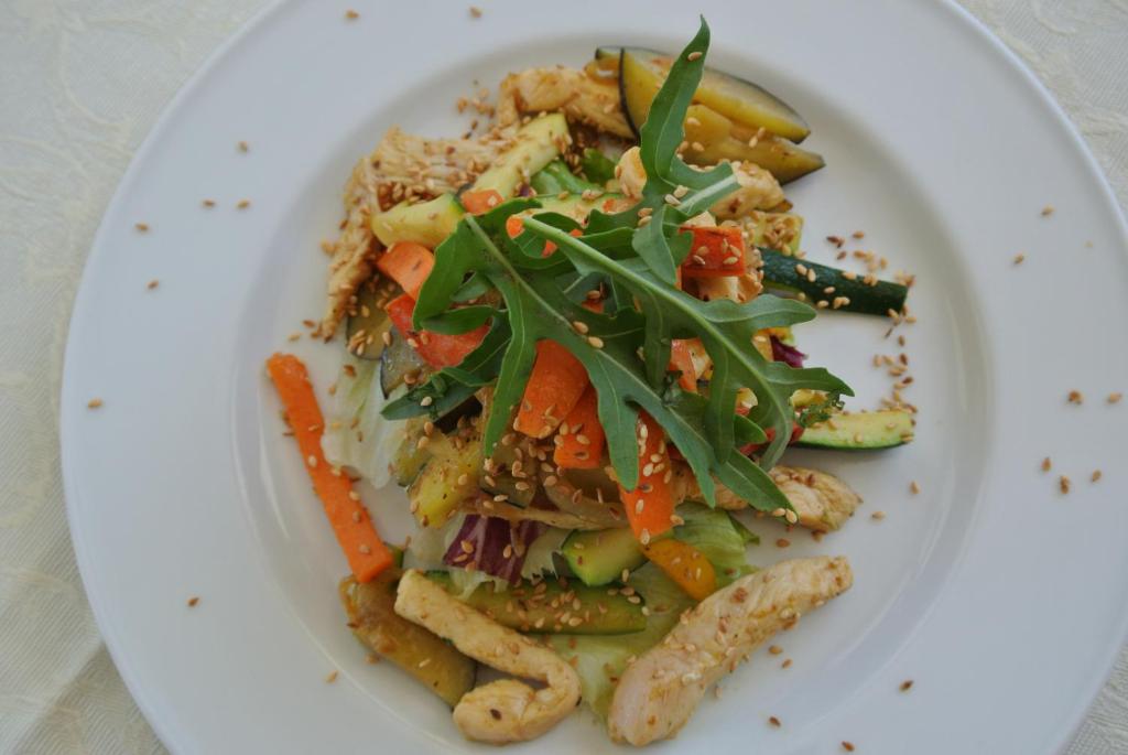 a plate of food with vegetables on a plate at Hotel Bologna in Lignano Sabbiadoro
