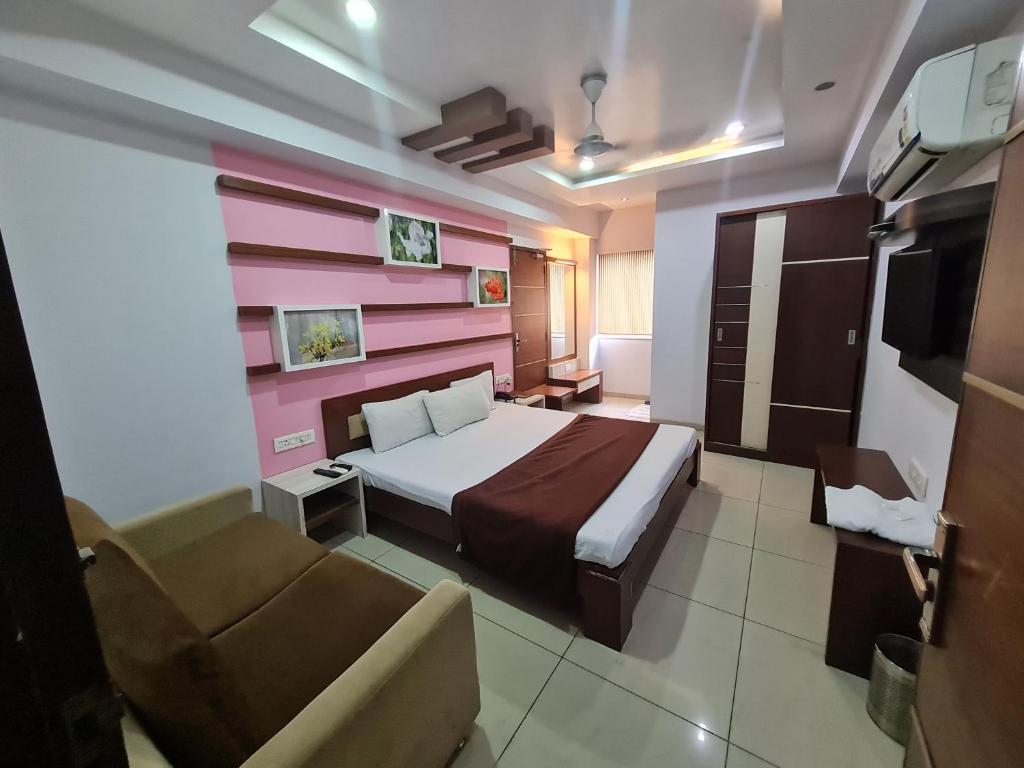 una camera con letto, sedia e divano di Hotel Kalinga Lake View a Ahmedabad