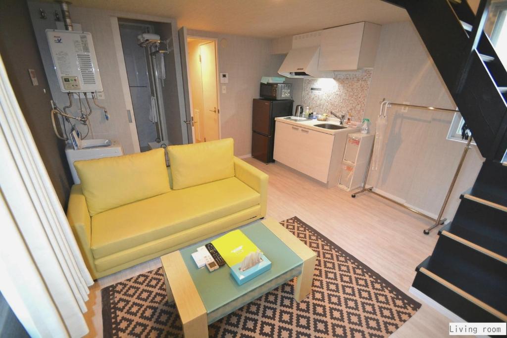 - un salon avec un canapé jaune et une table dans l'établissement Aparthotel Palais Royal with Parking, à Sapporo