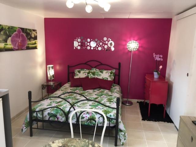 een slaapkamer met een bed met een paarse muur bij Gite des 2 arbres de la sagesse , agréable chalet avec spa privatif in Ardentes