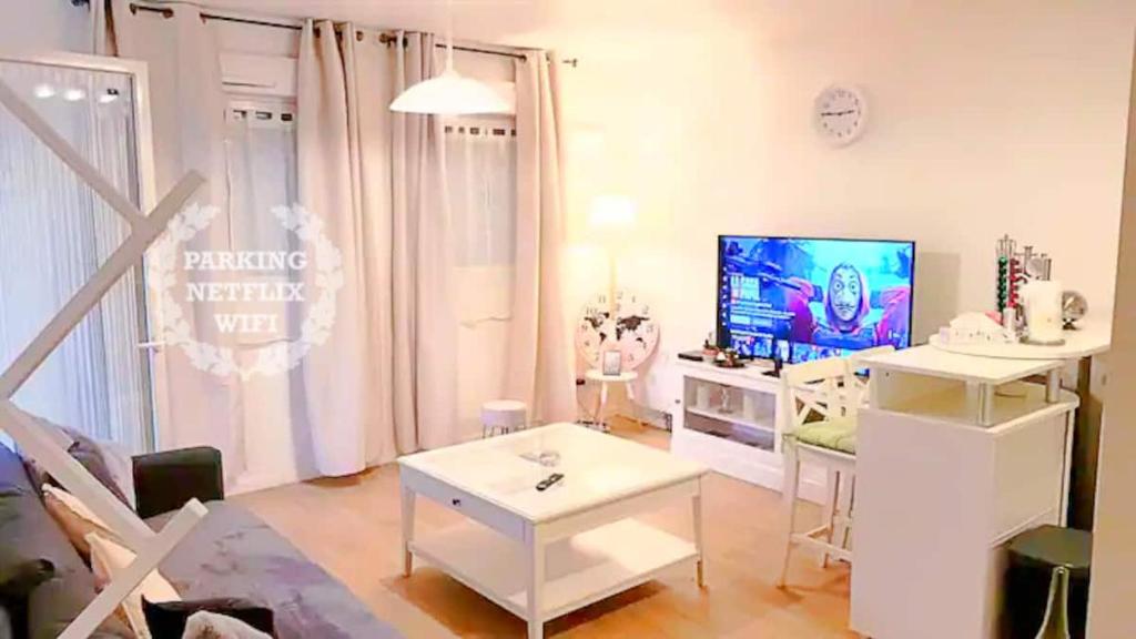 a white living room with a tv and a table at 1 APPART 2 PIECES NEUF PROCHE GARE PARKING NETFLIX Evry Courcouronnes in Evry-Courcouronnes