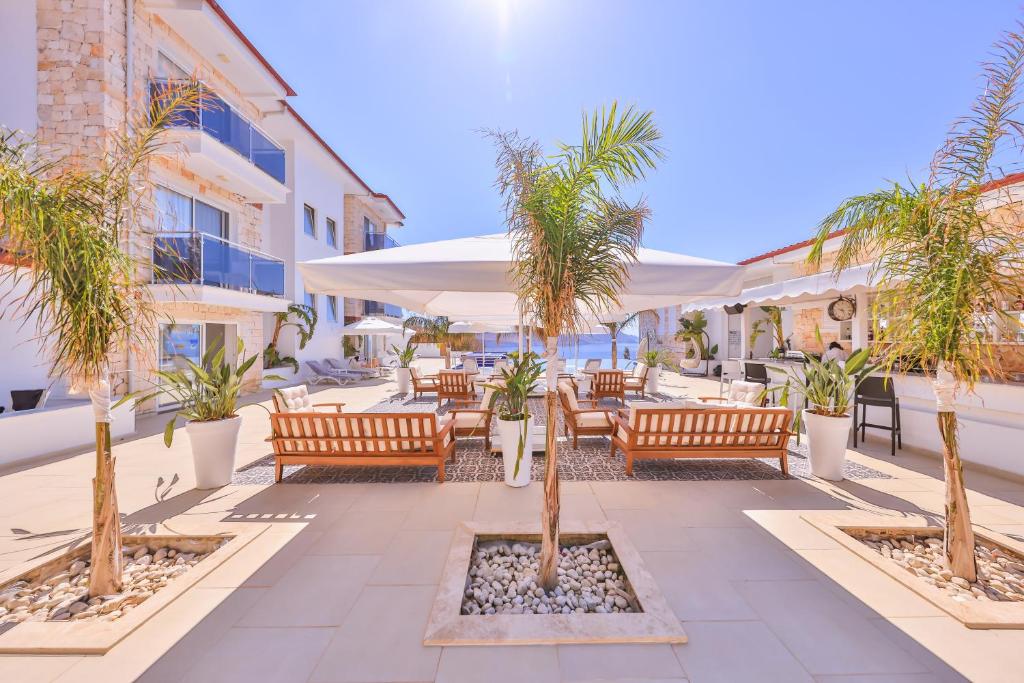 a patio with wooden benches and palm trees at La Kumsal Hotel in Kaş