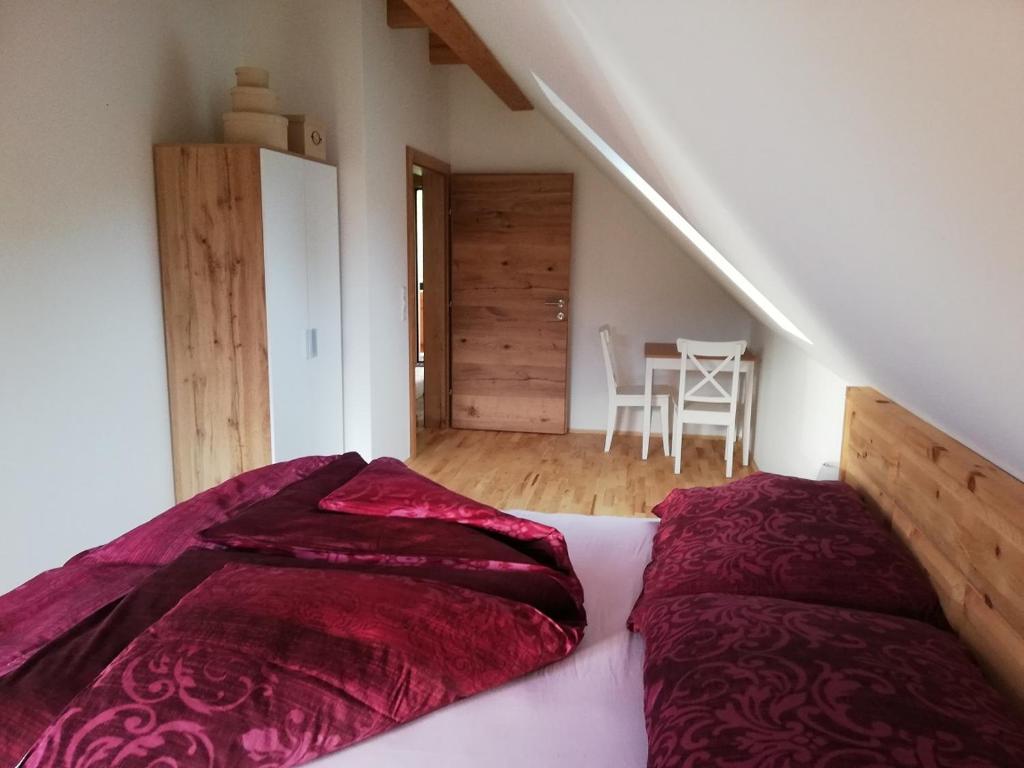 a bed with red sheets in a room with a staircase at Bioferienhaus Muster - Dominkusch in Pössnitz