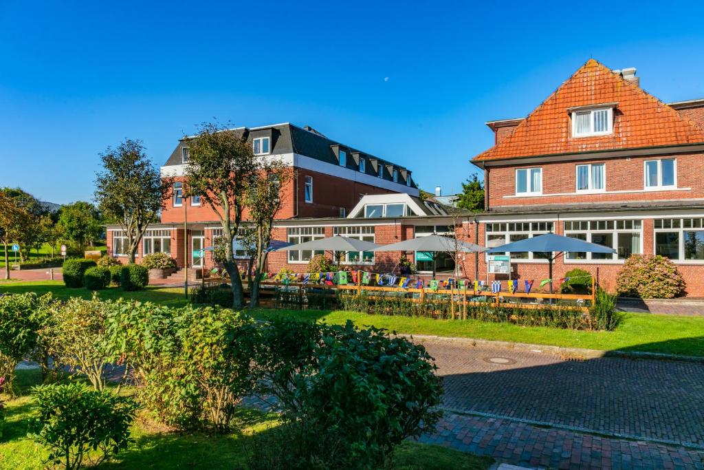 ein Hotel mit Tischen und Stühlen vor einem Gebäude in der Unterkunft Hotel Bethanien in Langeoog