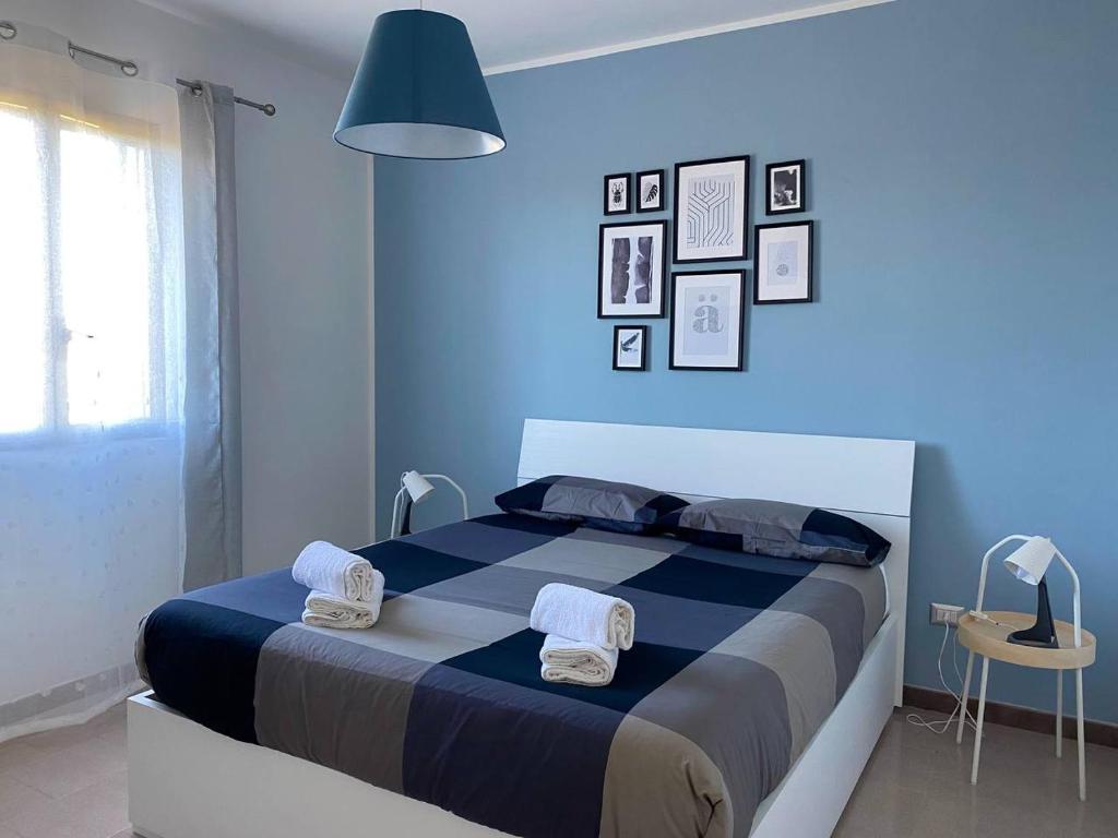 um quarto azul com uma cama com toalhas em HOME D&D em Niscemi