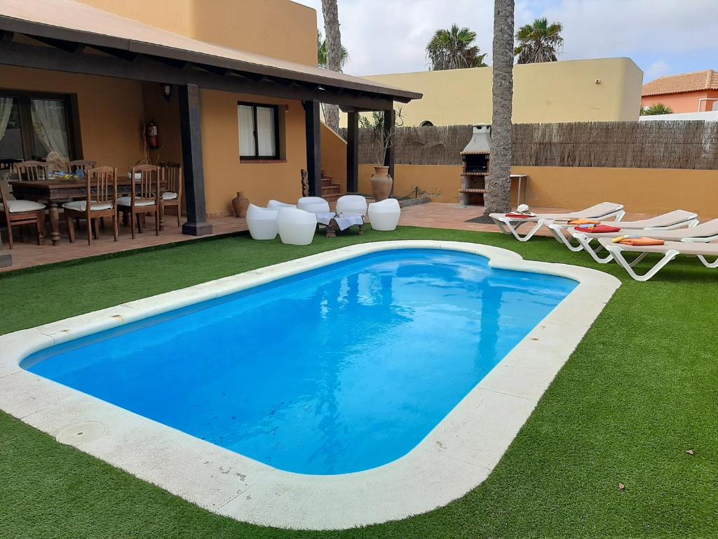 a swimming pool in a yard next to a house at Villa Coral in Corralejo