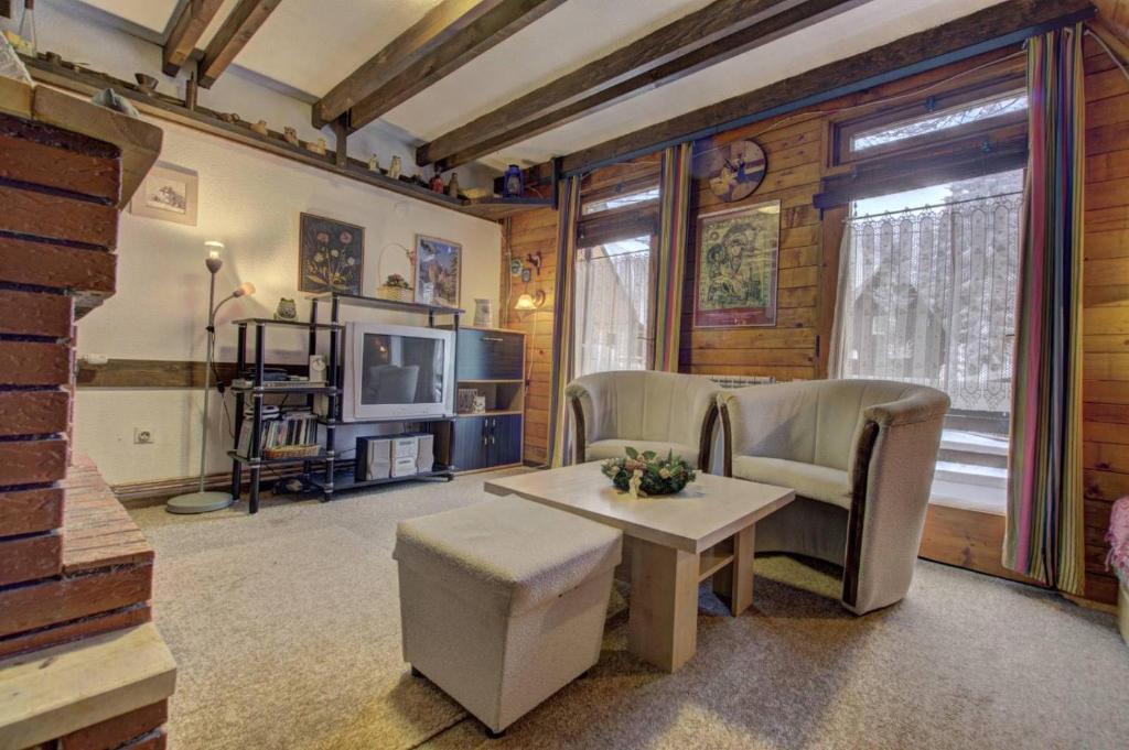 a living room with a table and chairs and a television at Planinska kuća Kamin in Jahorina