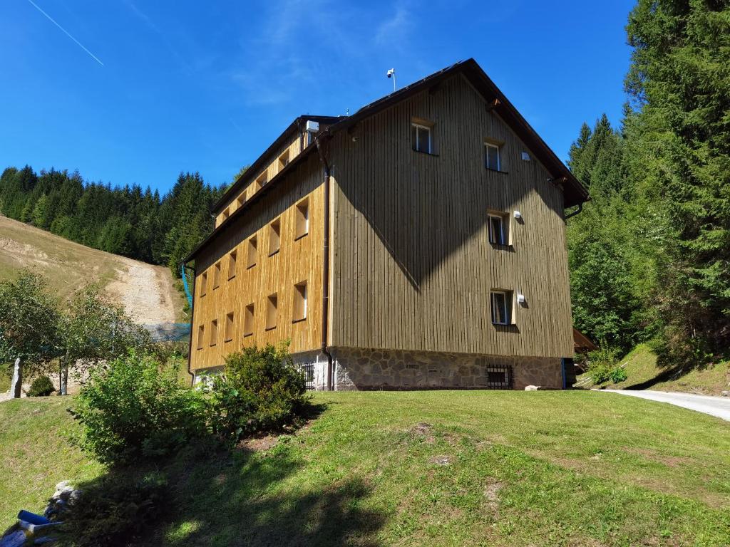 ein großes Holzgebäude auf einem Hügel mit Bäumen in der Unterkunft APARTMENTS ROGLA JURGOVO - Ski in Ski out in Lukanja