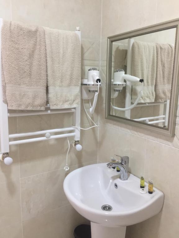 a bathroom with a sink and a mirror and towels at Guest House Marani in Sighnaghi