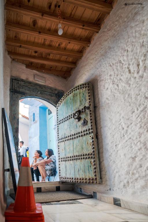 two people sitting on a bench next to a door at RIAD LA SANTA in Chefchaouen