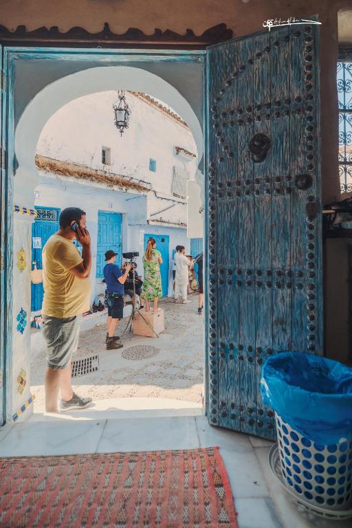 a man talking on a cell phone in front of a door at RIAD LA SANTA in Chefchaouen