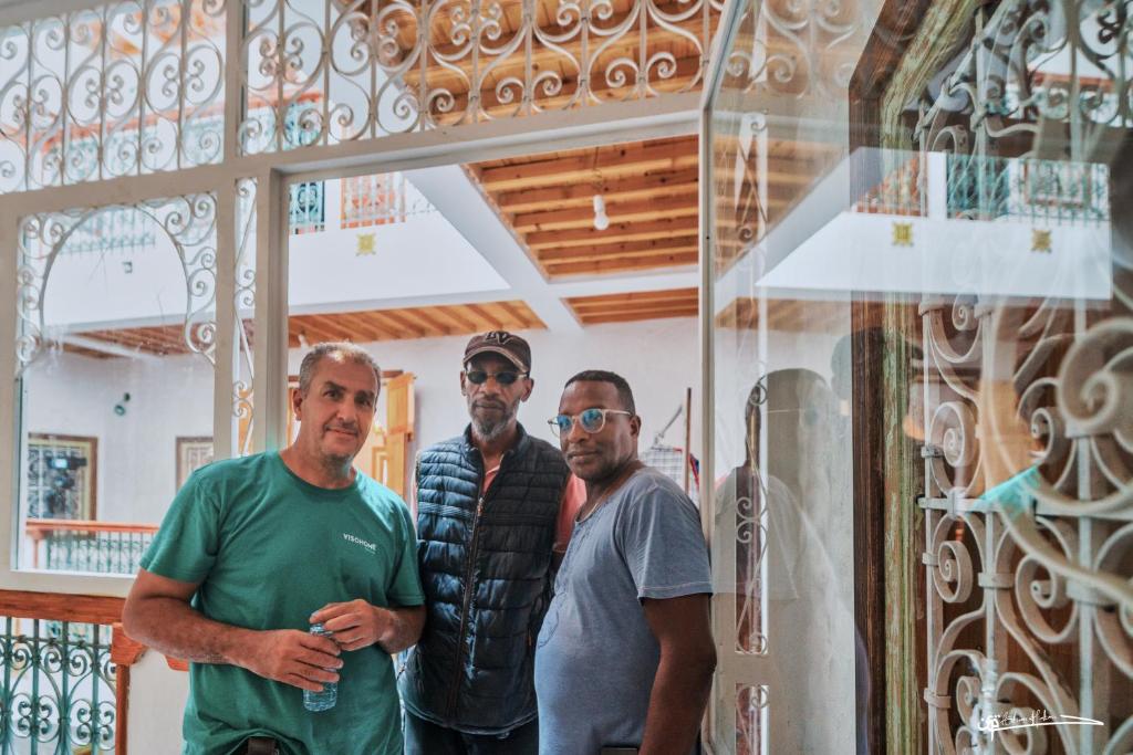 a group of three men standing in front of a window at RIAD LA SANTA in Chefchaouen