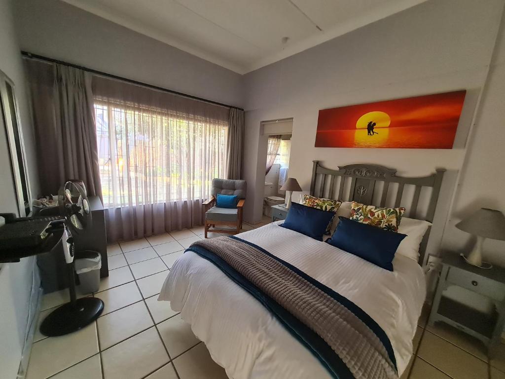 a bedroom with a large bed with blue pillows at The Garden Inn Guesthouse in Modimolle