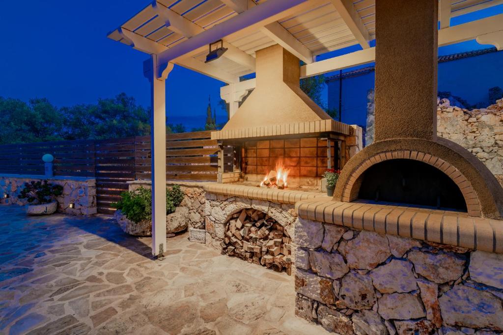 a stone fireplace in a patio with a gazebo at Villa Daniela in Koríthion