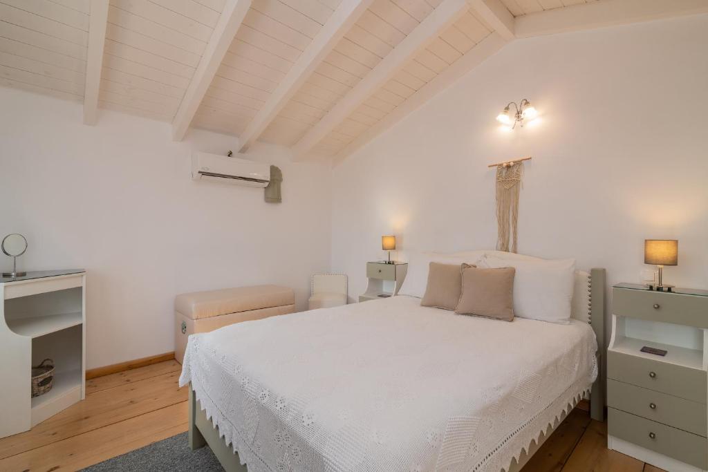 a white bedroom with a white bed and two lamps at Villa Daniela in Koríthion