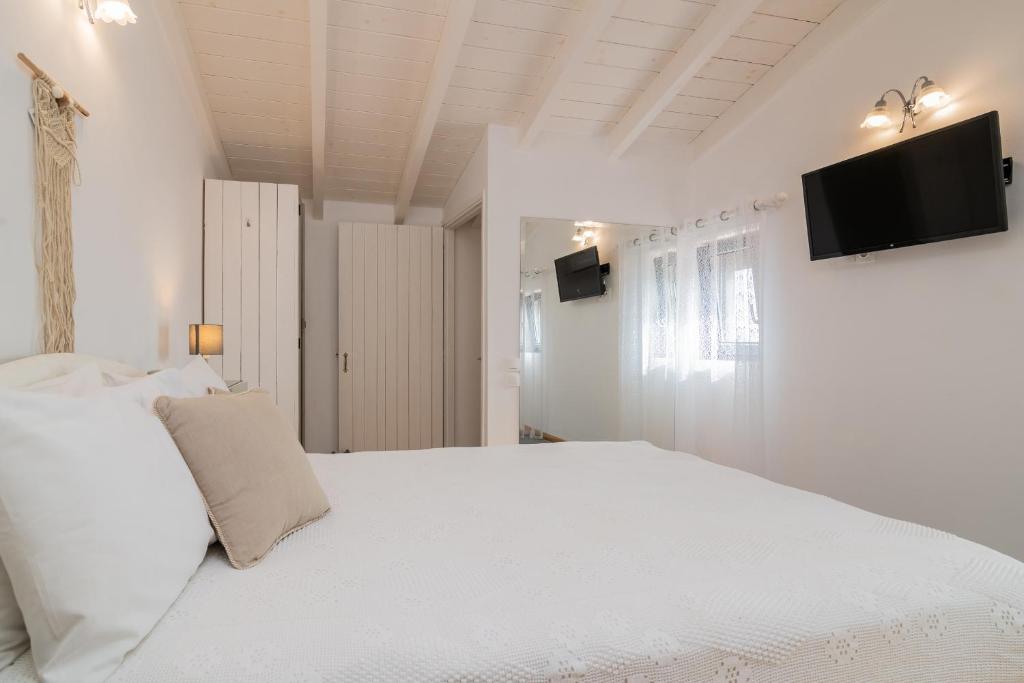 a white bedroom with a white bed and a tv on the wall at Villa Daniela in Koríthion
