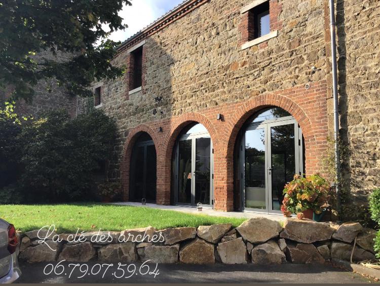 a brick building with a stone wall in front of it at Chambres d hôtes La clé des arches in Sainte-Florine