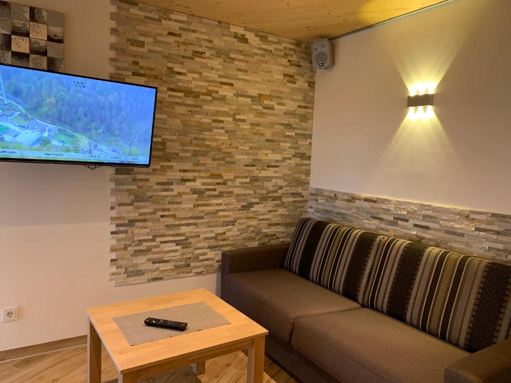 ein Wohnzimmer mit einem Sofa und einem Flachbild-TV in der Unterkunft Chalet Mia in Wängle bei Reutte in Reutte