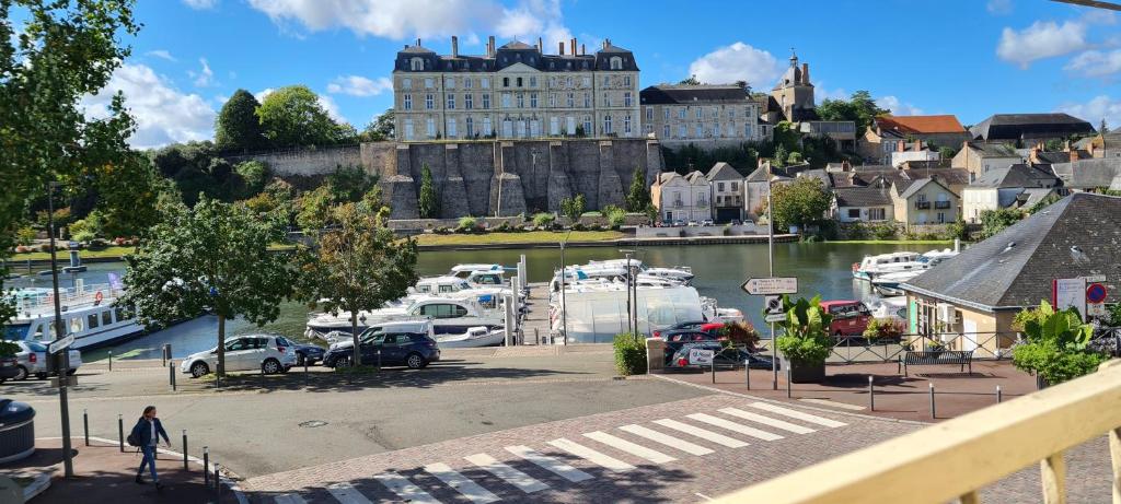 un port de plaisance avec des bateaux dans l'eau et un château dans l'établissement Cosy idéal, appart vue sur le port et le château, plein centre, stationnement facile, à Sablé-sur-Sarthe