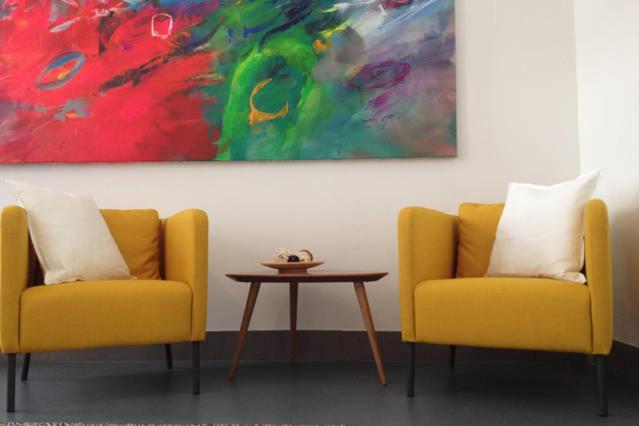 Dos sillas amarillas y una mesa en una habitación con una pintura en Stylish holiday Art apartment - wifi & great location en Budapest