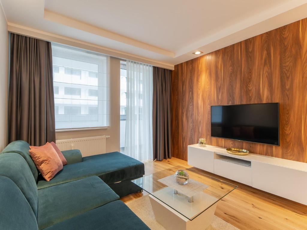 ein Wohnzimmer mit einem blauen Sofa und einem Flachbild-TV in der Unterkunft Apartament Premium Bliżej Morza in Kołobrzeg