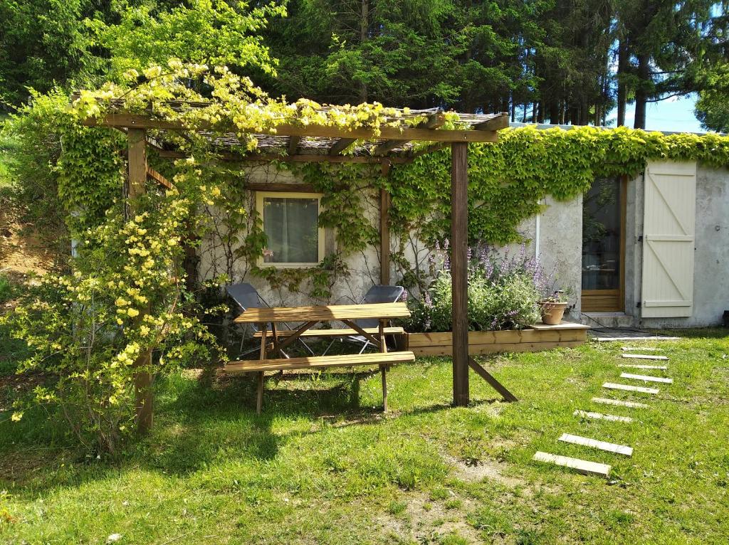 uma pérgola com uma mesa de piquenique e cadeiras num quintal em Les Granges de la hulotte, les Mésanges em Lies