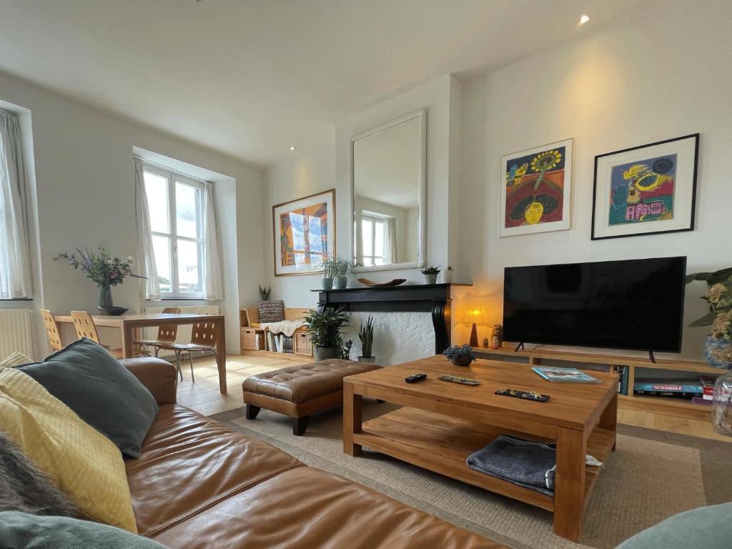 a living room with a couch and a flat screen tv at Appartement et parking privatif le long de l Escaut in Tournai