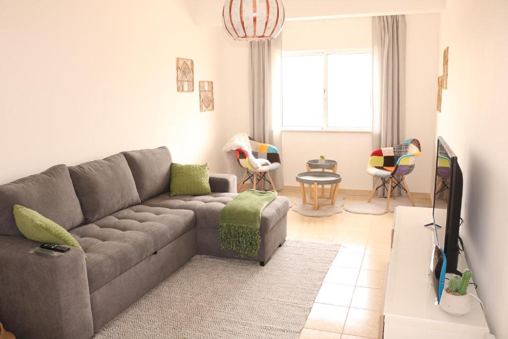 uma sala de estar com um sofá cinzento e cadeiras em Casa do Mar - Apartamento com vista Ria e Mar na Fuzeta