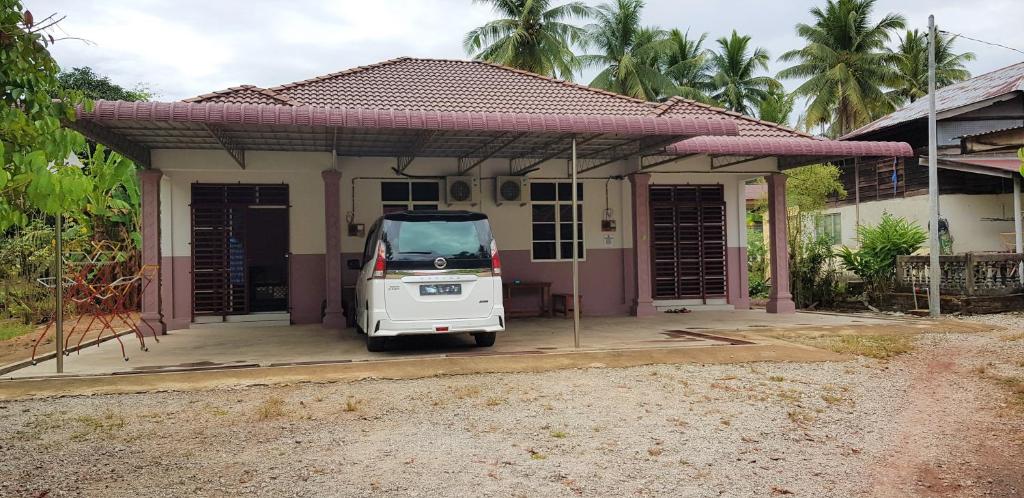 a small white car parked in front of a house at Tok Chik Homestay in Kampong Lubok Bedil