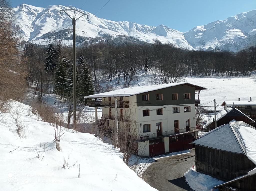 a building in the snow with mountains in the background at Logis Saint Roch in Saint-François-Longchamp