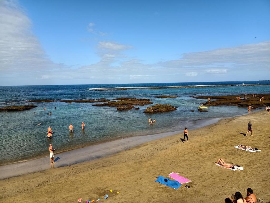 un groupe de personnes dans l'eau d'une plage dans l'établissement Estudio W&G Las Canteras con bonitas vistas al mar, à Las Palmas de Gran Canaria