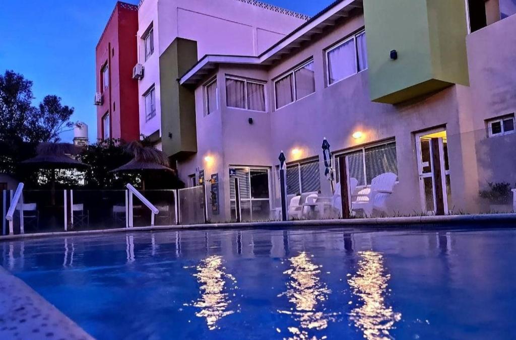 una casa con piscina di fronte a un edificio di Hostería Magnolia a Villa Gesell