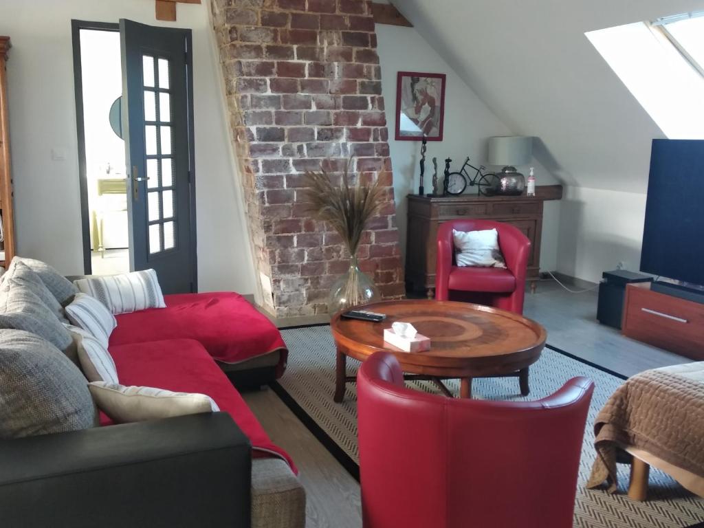 ein Wohnzimmer mit roten Möbeln und einer Ziegelwand in der Unterkunft Suite familiale Mamito et Papito in Notre-Dame-du-Bec