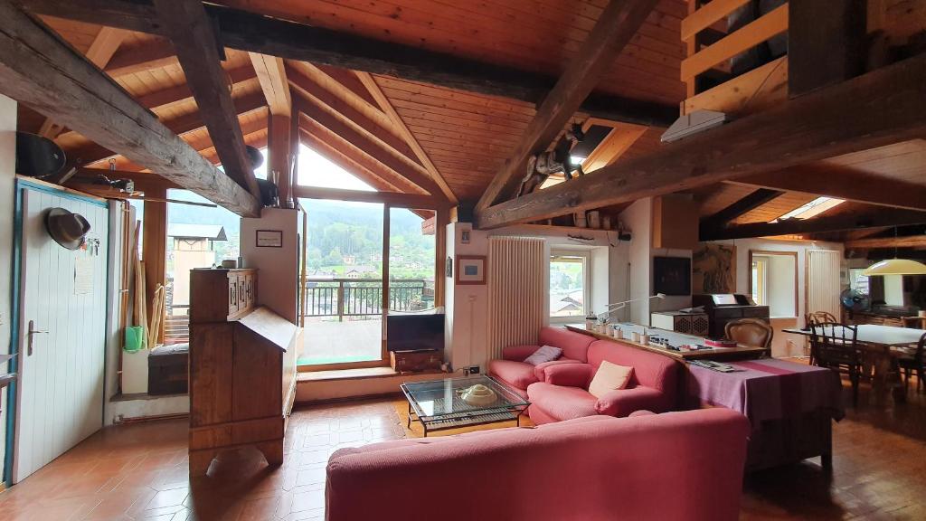 a living room with a red couch and a table at Soffitta Loft panoramico in Fiera di Primiero