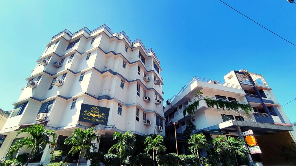 a tall white building with palm trees in front of it at Dodas Palace by Asapian Hotels in Jaipur