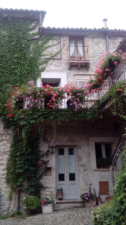 un edificio con flores a un lado. en la Casa sull'arco - Albergo diffuso Collelungo, en Collelungo