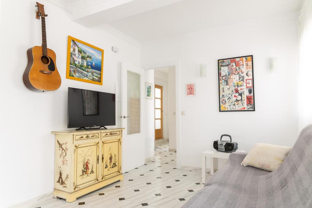 ein Wohnzimmer mit einem Fernseher und einer Gitarre an der Wand in der Unterkunft Castillo in Estepona
