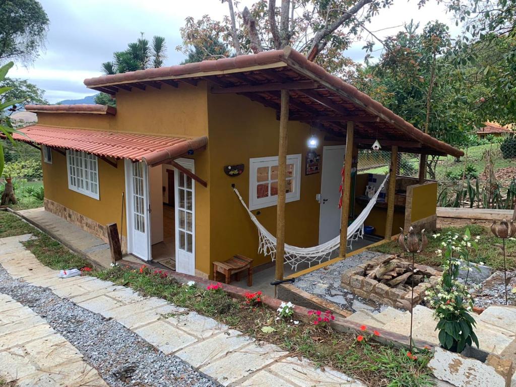 a small yellow house with a hammock in front of it at Loft do Alto-Araras in Petrópolis