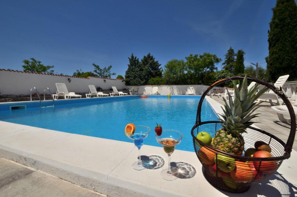 een fruitmand en wijnglazen naast een zwembad bij Rooms Aurora in Pula