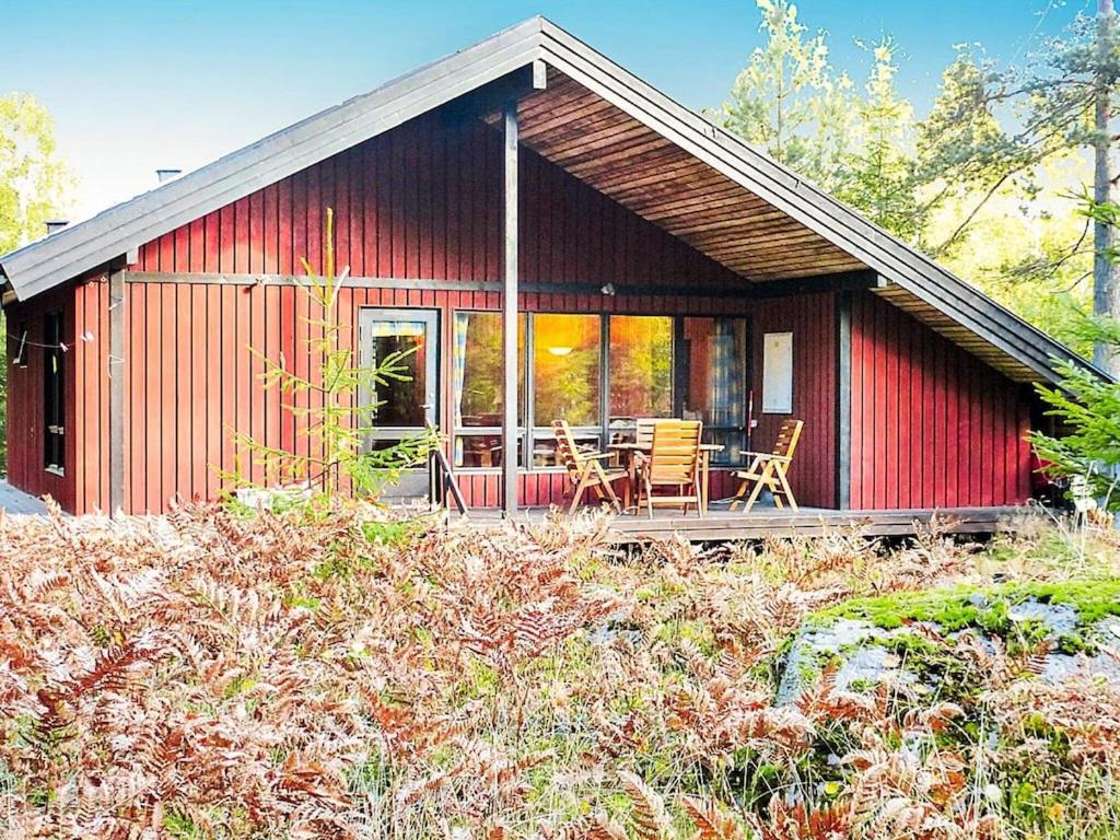 ein rotes Haus mit einem Tisch und Stühlen davor in der Unterkunft Holiday home HOLMSJÖ II in Troxhult