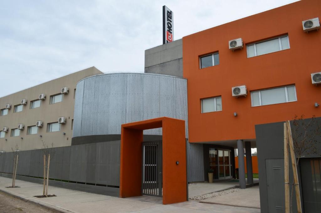 een oranje gebouw met een oranje deur voor de deur bij Hotel Bait in General Roca