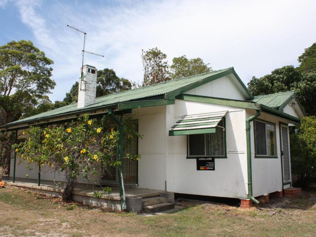 a white house with a lemon tree in front of it at Luka Land in Iluka