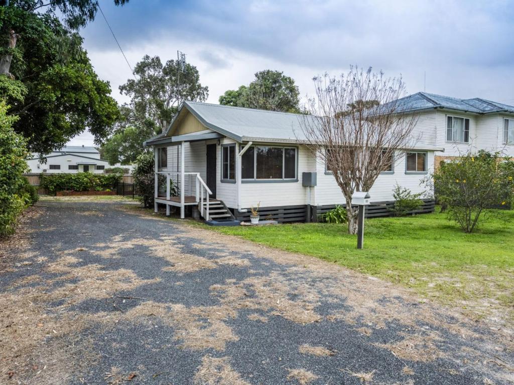 a white house with a driveway in front of it at Salt Water Cottage in Iluka