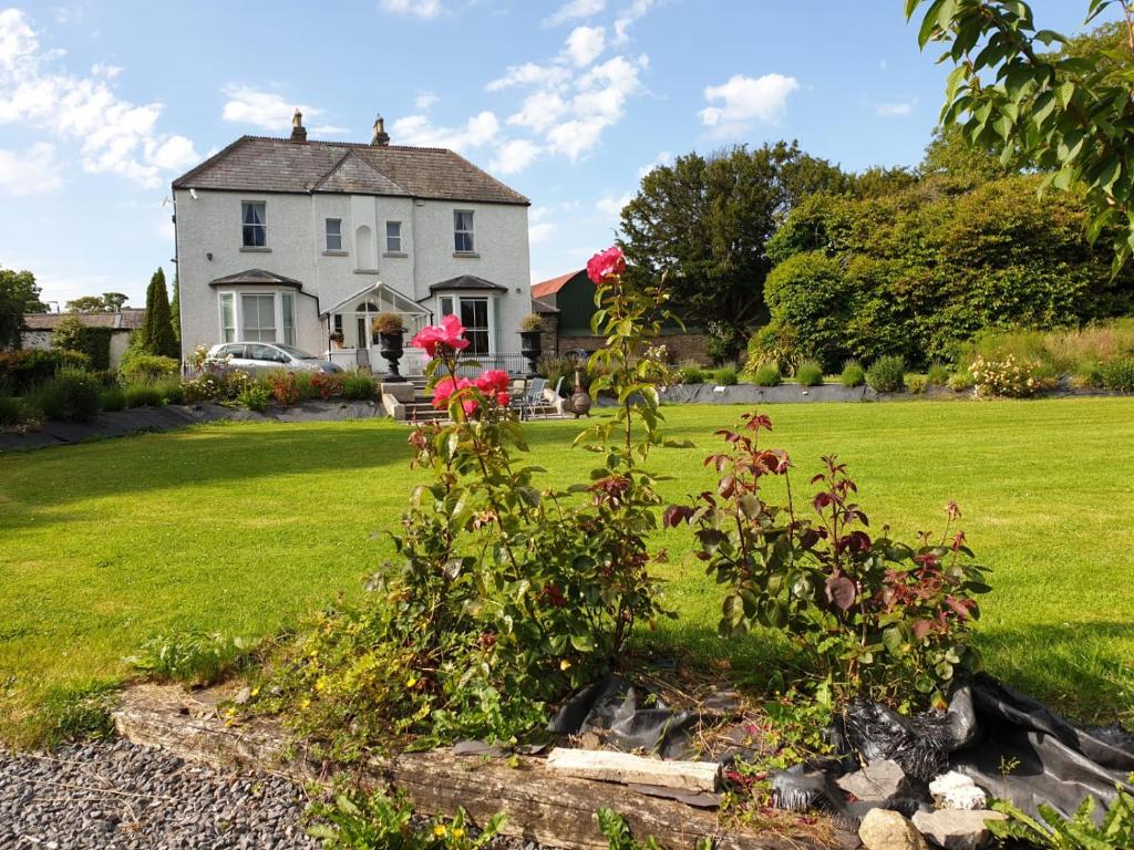 uma casa com um arbusto de flores num quintal em Mount Pleasant Country House em Lucan